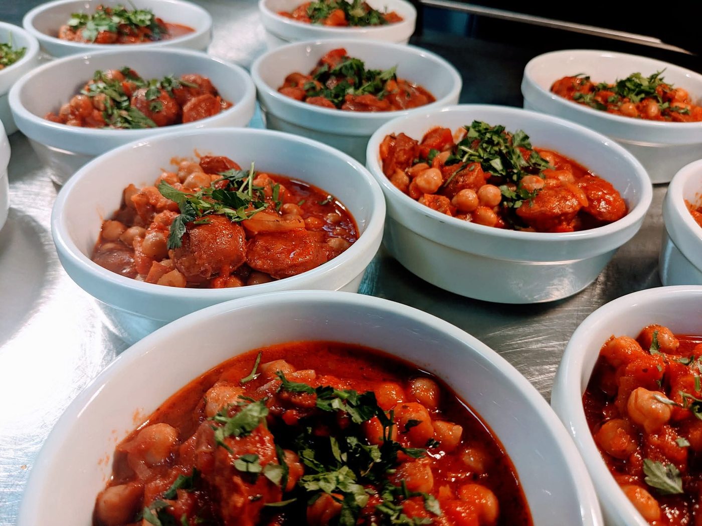 Bowls of chorizo and chickpea stew plated for lunch service