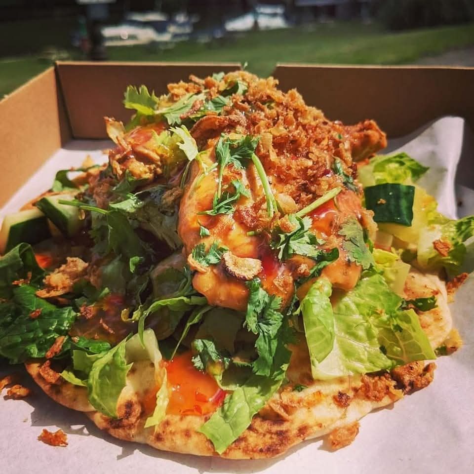 A loaded flatbread with salad, crispy onions and sauce